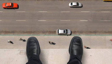 A man standing on a ledge on a building as if ready to jump.